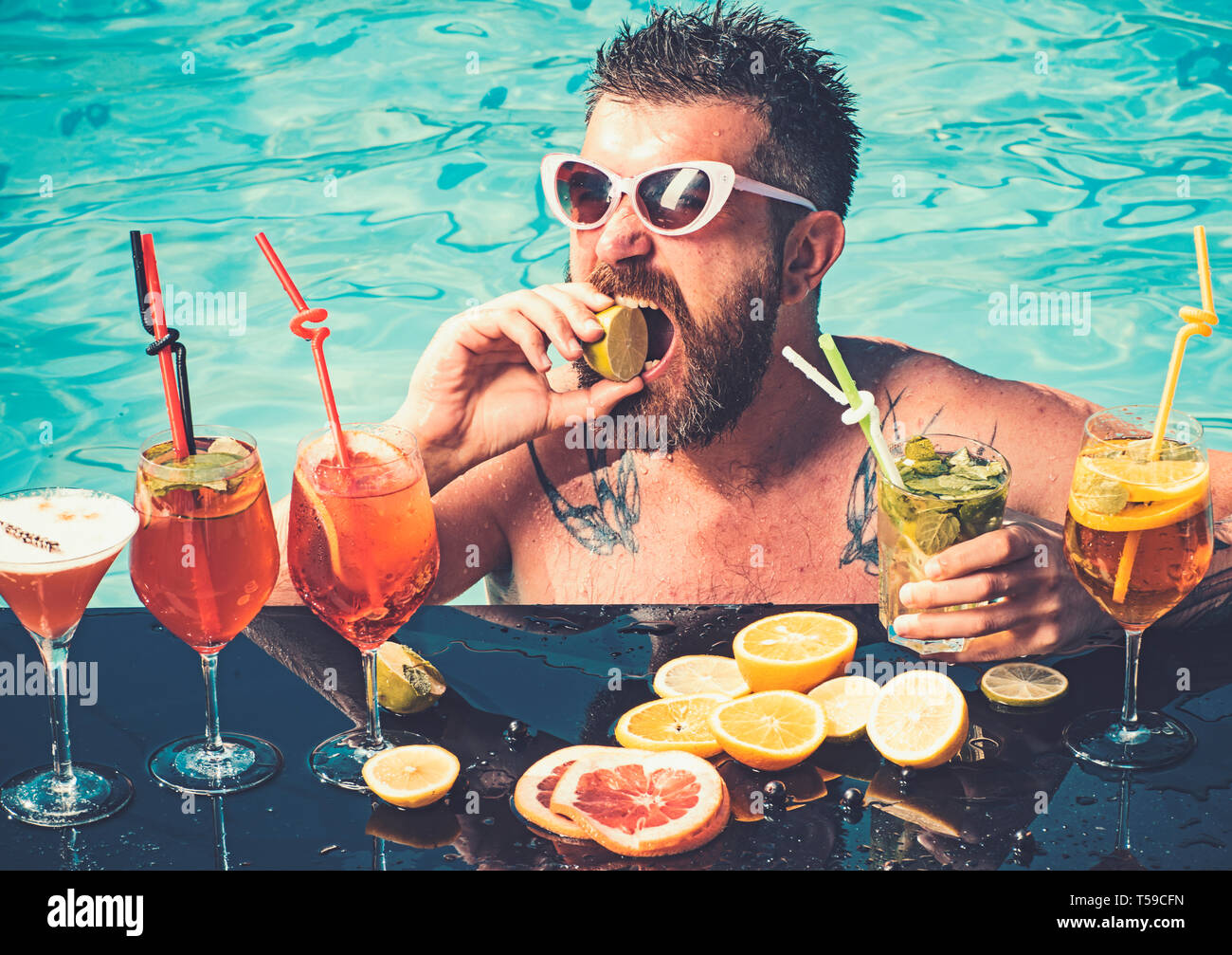 Entspannen Sie sich am Meer und Spa Resort. Cocktail mit Obst in der bärtigen Mann im Pool. Pool Party, Vitamin- und nähren. Mann Schwimmen und trinken Alkohol. Sommer Stockfoto