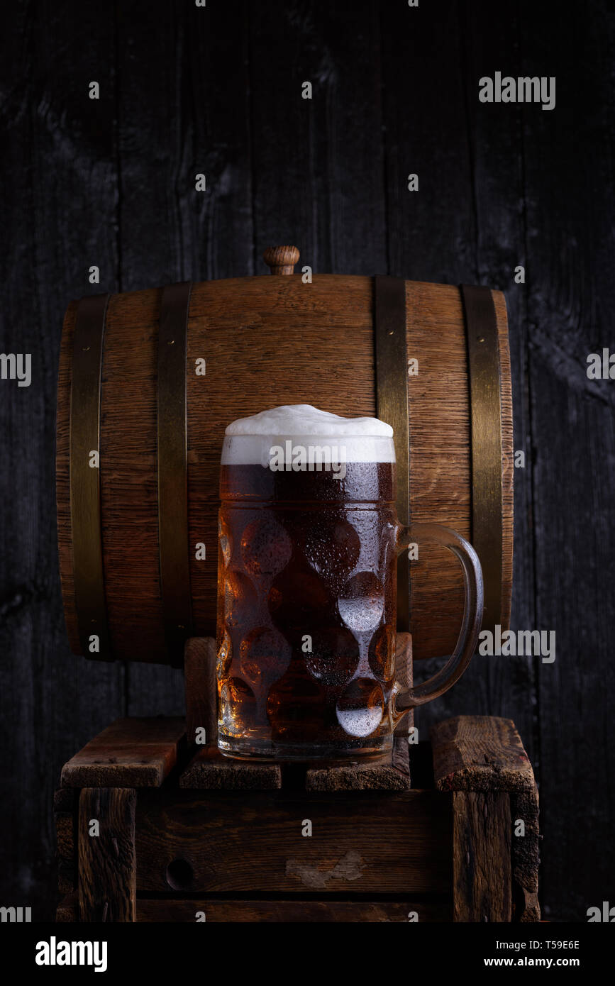 Riesige Bierkrug auf alten Holzkiste mit Vintage Barrel Bier auf Hintergrund Stockfoto