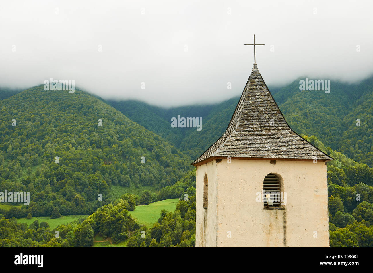 Pfarrkirche St. Martin Glockenturm mit Aspe Landschaft mit Wäldern und Wiesen im Hintergrund (Aydius, CC Vallée Aspe, Aquitaine, Frankreich) Stockfoto