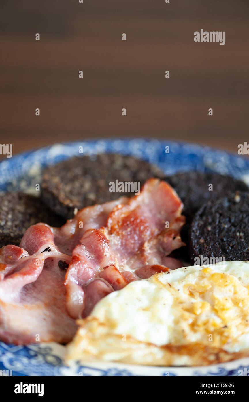 Warmes Frühstück mit Speck, Spiegelei, Blutwurst in Scheiben geschnitten und Haggis. Stockfoto