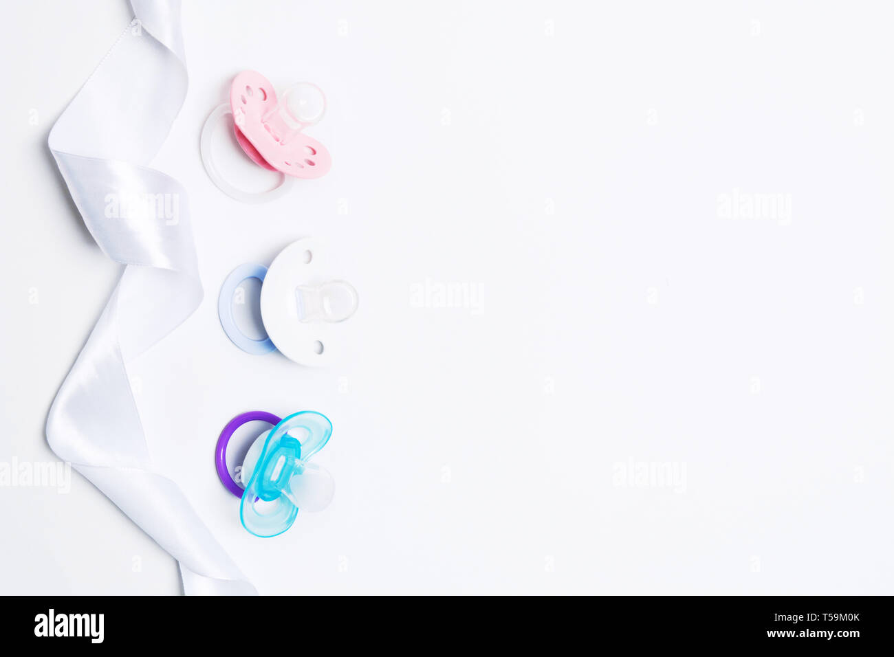 Baby Dusche mit drei bunten Baby Silikon Schnuller mit Halter mit Band auf weißem Hintergrund. Mock up. Flach. Ansicht von oben. Kieferorthopädische dummy für Stockfoto