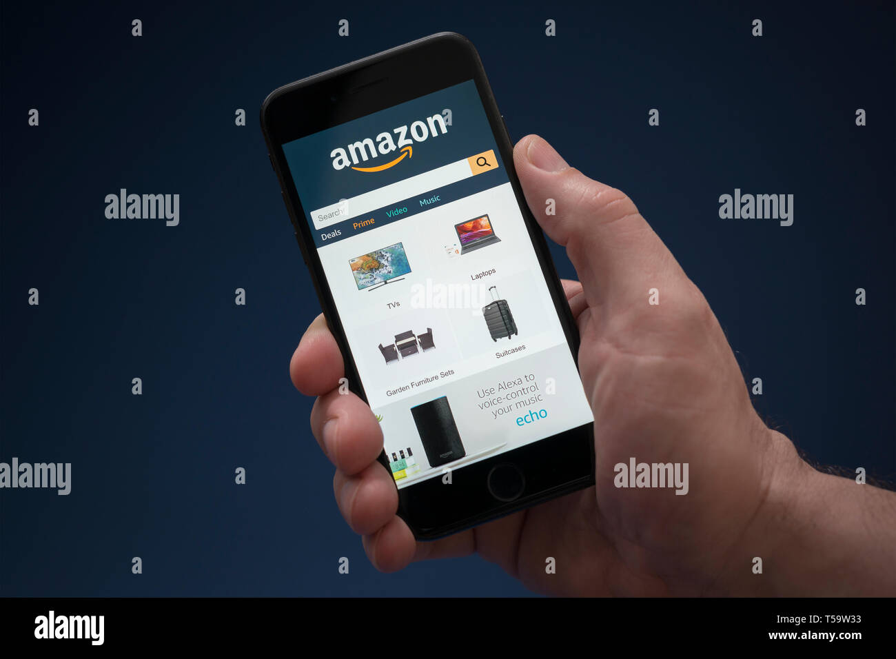 Ein Mann schaut auf seinem iPhone. Das Amazon-Logo (nur redaktionelle Nutzung). Stockfoto