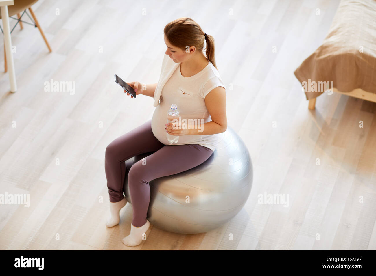 Schwangere Frau sitzt auf Fitness Ball Stockfoto