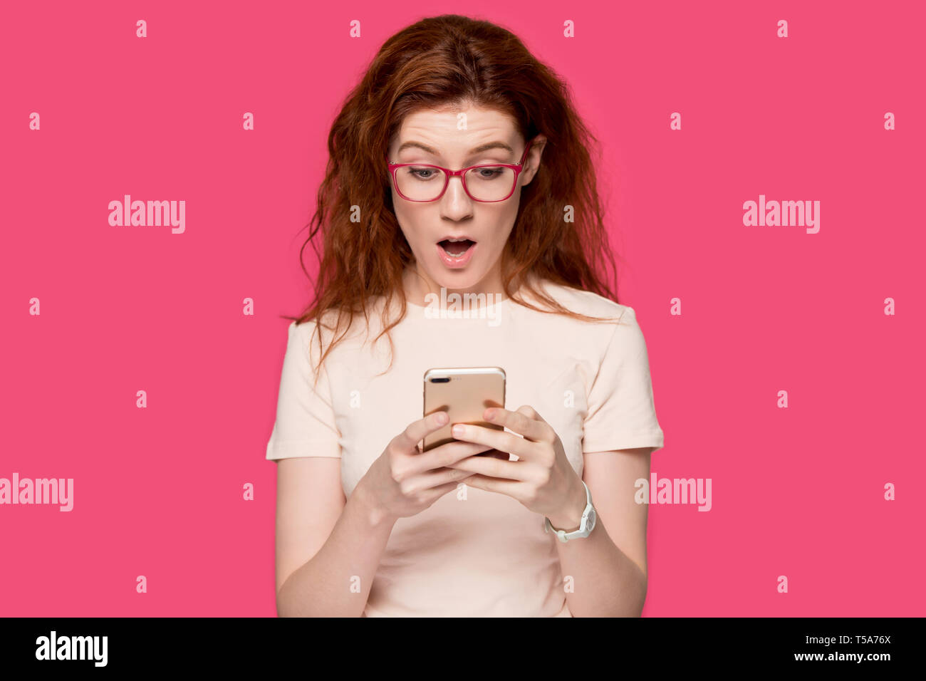 Erstaunt rothaarige Mädchen lesen schockierende online Nachrichten auf Zelle Stockfoto