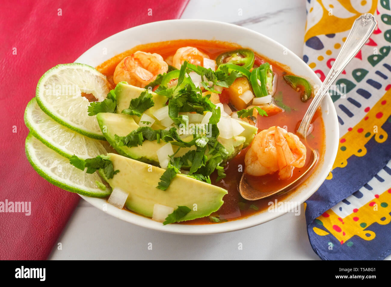 Würzige mexikanische Garnelen Suppe Caldo de Camaron mit Avocado gewürfelte Zwiebeln, Koriander und Limettensaft Keil garnieren Stockfoto