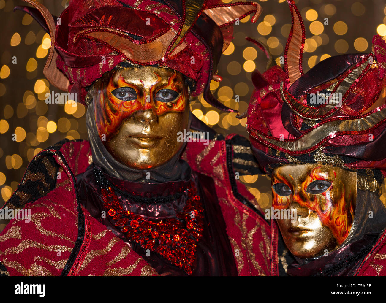 Karneval in Venedig paar Feuer rot tragen Masken und Kostüme, Italien, Nachtporträt mit bokeh Lichter Hintergrund Stockfoto