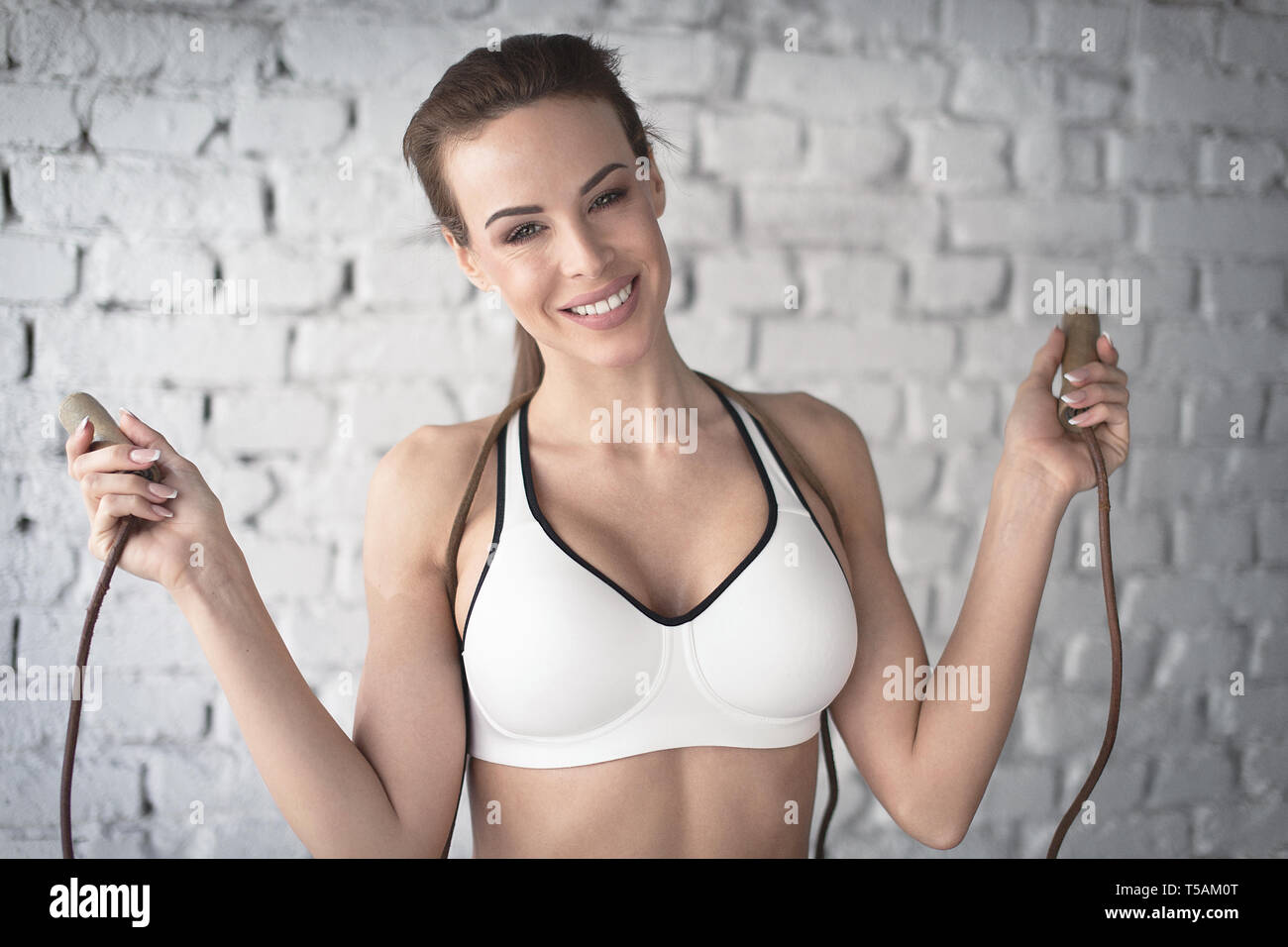 Glückliche junge Frau ist sport-Bh holding Seil springen Portrait, toothy Lächeln und Glück Stockfoto