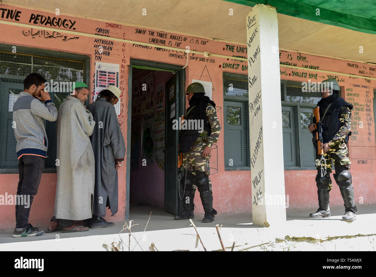 Die regierungstruppen gesehen stehen auf der Hut wie Kaschmir Wähler in einer Warteschlange stehen, ihre Stimmen vor einem Wahllokal in Anantnag, in Kaschmir zu werfen. In der dritten Phase der Parlamentswahlen in Indien Wahlen, Inder gingen nach Umfragen unter komplett heruntergefahren und internet Gag. Stockfoto