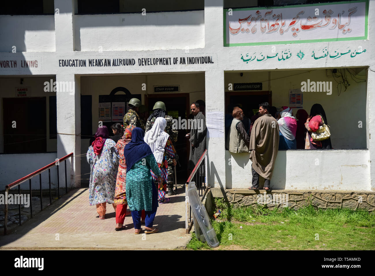 Die regierungstruppen gesehen stehen auf der Hut wie Kaschmir Wähler in einer Warteschlange stehen, ihre Stimmen vor einem Wahllokal in Anantnag, in Kaschmir zu werfen. In der dritten Phase der Parlamentswahlen in Indien Wahlen, Inder gingen nach Umfragen unter komplett heruntergefahren und internet Gag. Stockfoto