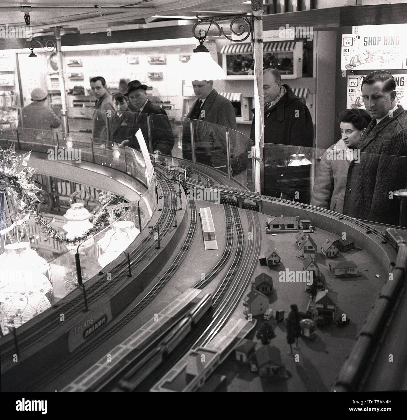 1950, historische, Personen, die in einem großen Zug set, Tri-ang Eisenbahn, in der Mitte des Hamleys Toy Shop, London, England angezeigt. Stockfoto