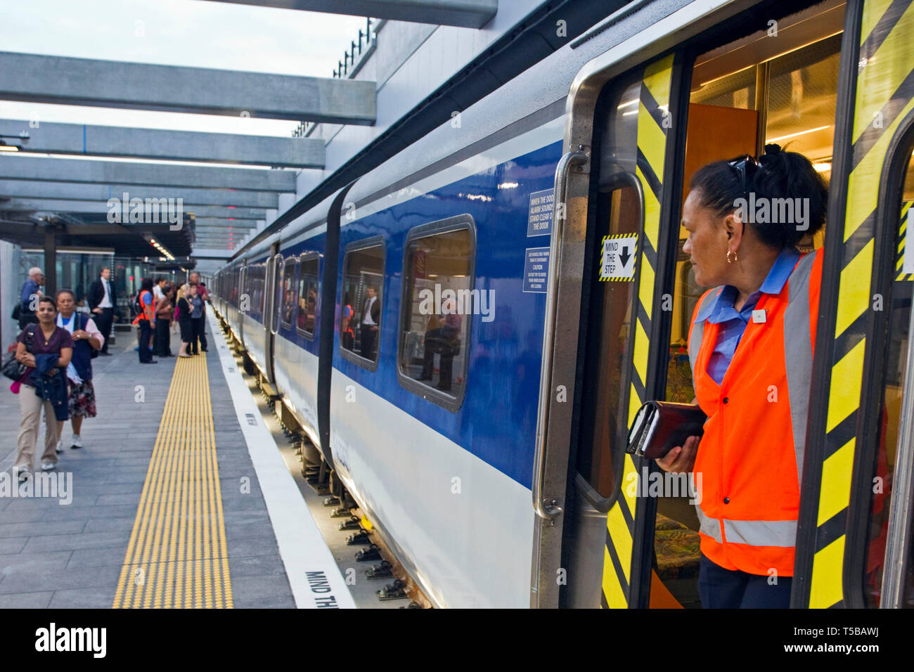 Ein zugbegleiter betreut Passagiere einen der ersten Züge durch die neue Lynn Rail Graben, Auckland, Neuseeland, Montag, bis 18. März Stockfoto