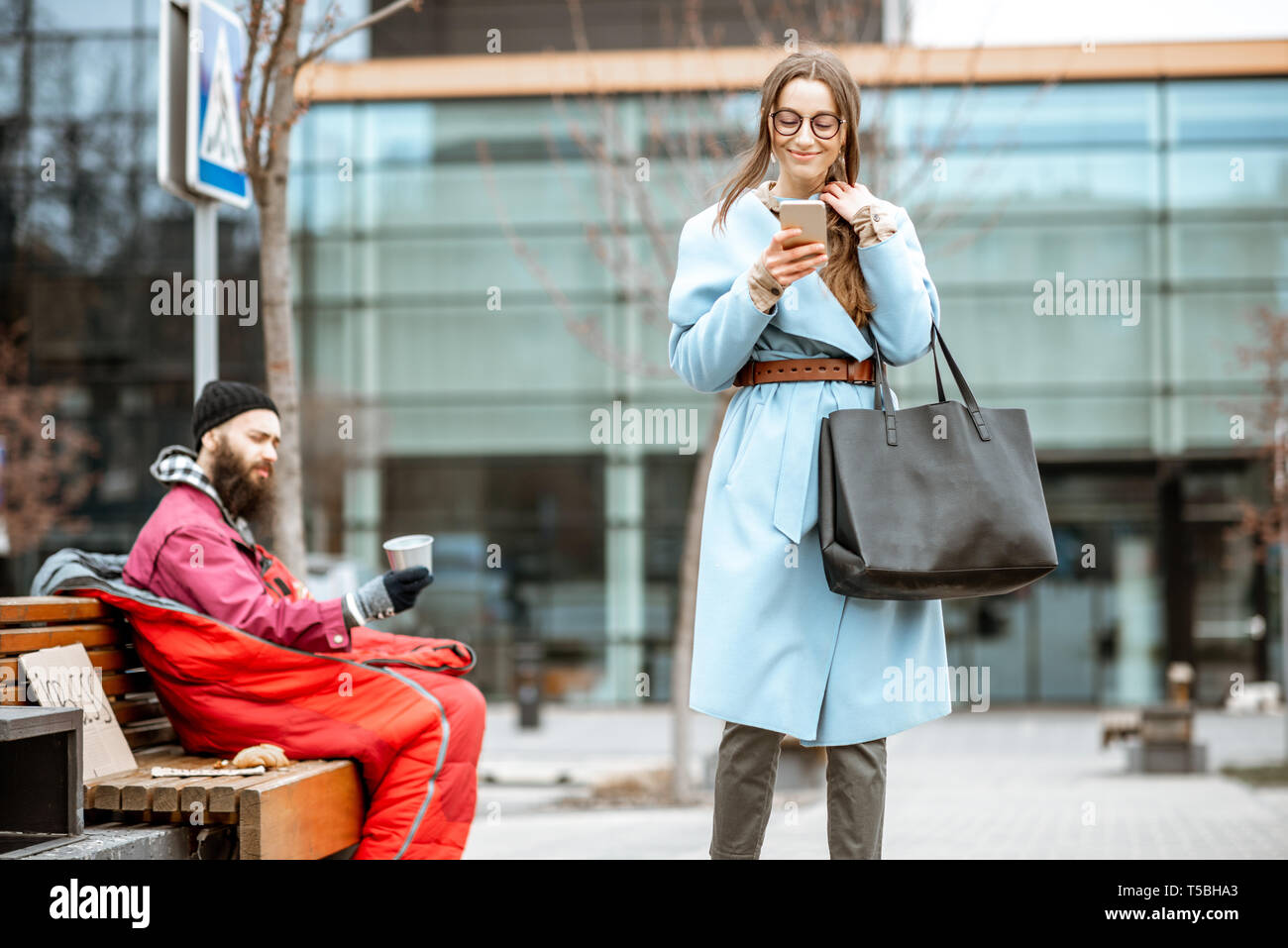 Obdachlose betteln um Geld, während Sie auf der Bank sitzen, die mit dem Übertragen von geschäftsfrau in der Nähe der Business Center Stockfoto