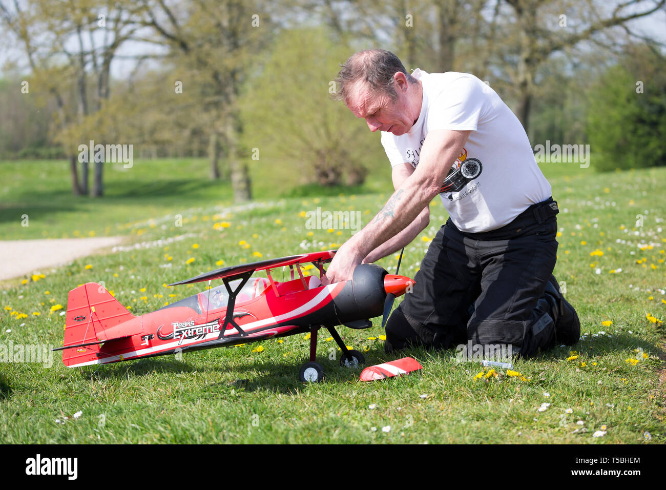 Nahaufnahme von Mann in Country Park (der Controller) kniend auf Gras, zur Festsetzung der Empfänger/Anpassungen an seinen Funkgesteuerten, flugmodell Flugzeug. Stockfoto