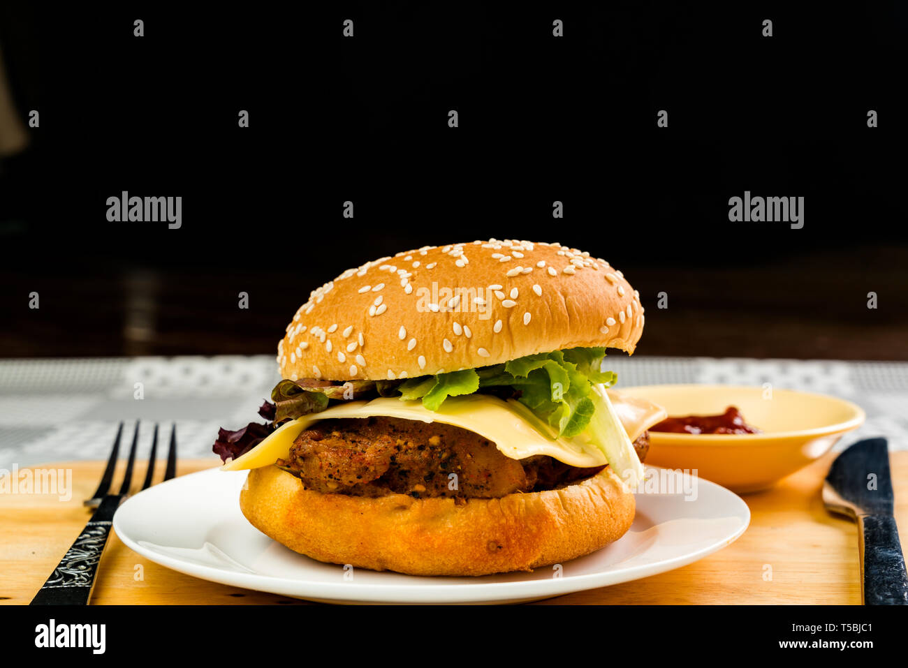 Hausgemachte Chicken Burger mit Käse und Gemüse in weiße Platte auf einem Holzbrett Stockfoto