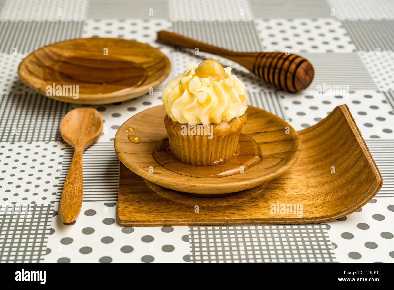 Cupcake und natürlichem Honig in eine hölzerne Platte mit Löffel aus Holz und Holz- Honig Pendelarm stick Stockfoto