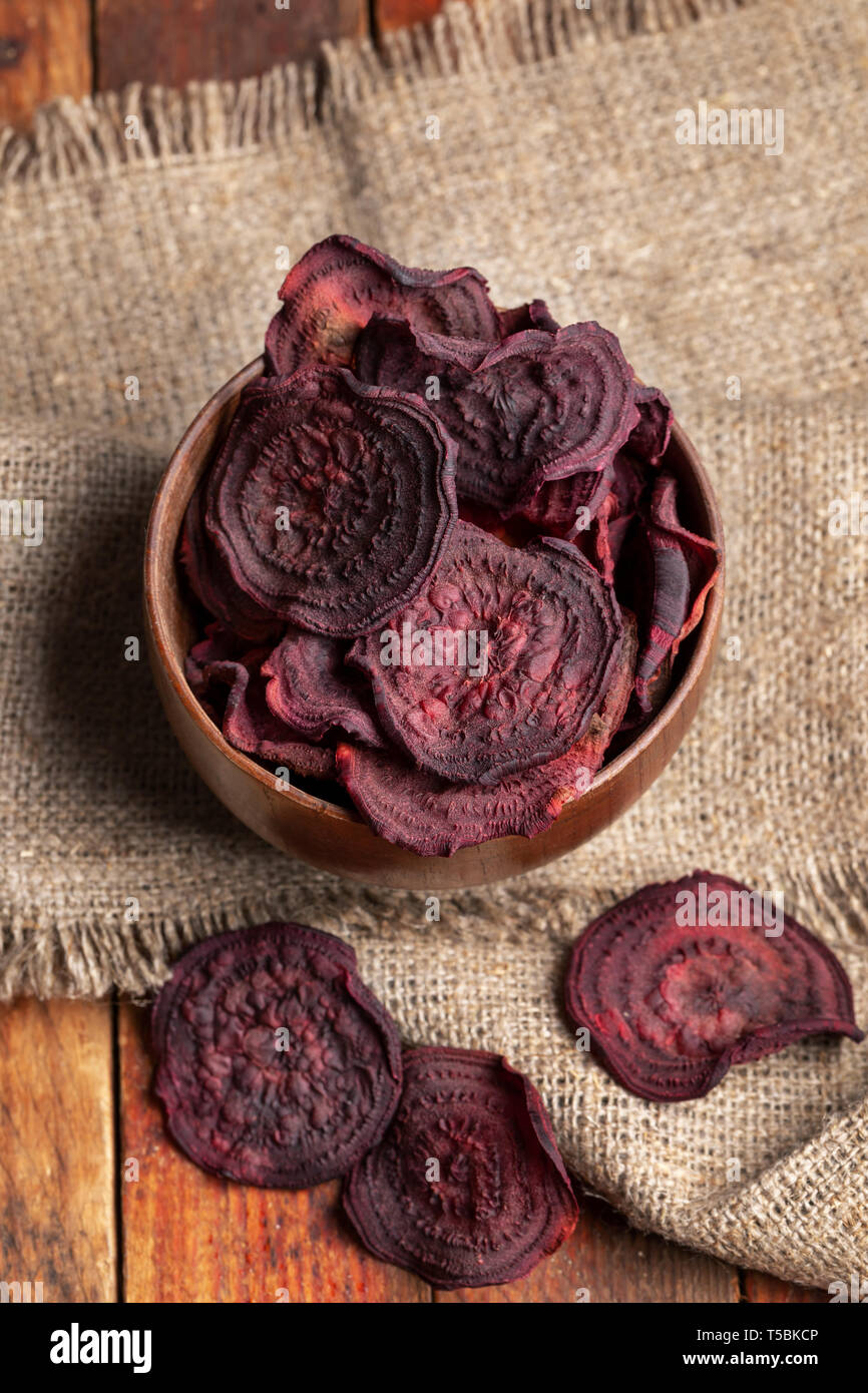 Ansicht von oben Rote Bete Chips in Houten auf sackleinen Serviette auf alten Holztisch. Stockfoto