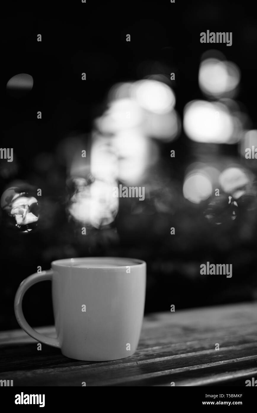 Kaffeetasse auf hölzernen Tisch im Restaurant bei Nacht Stockfoto