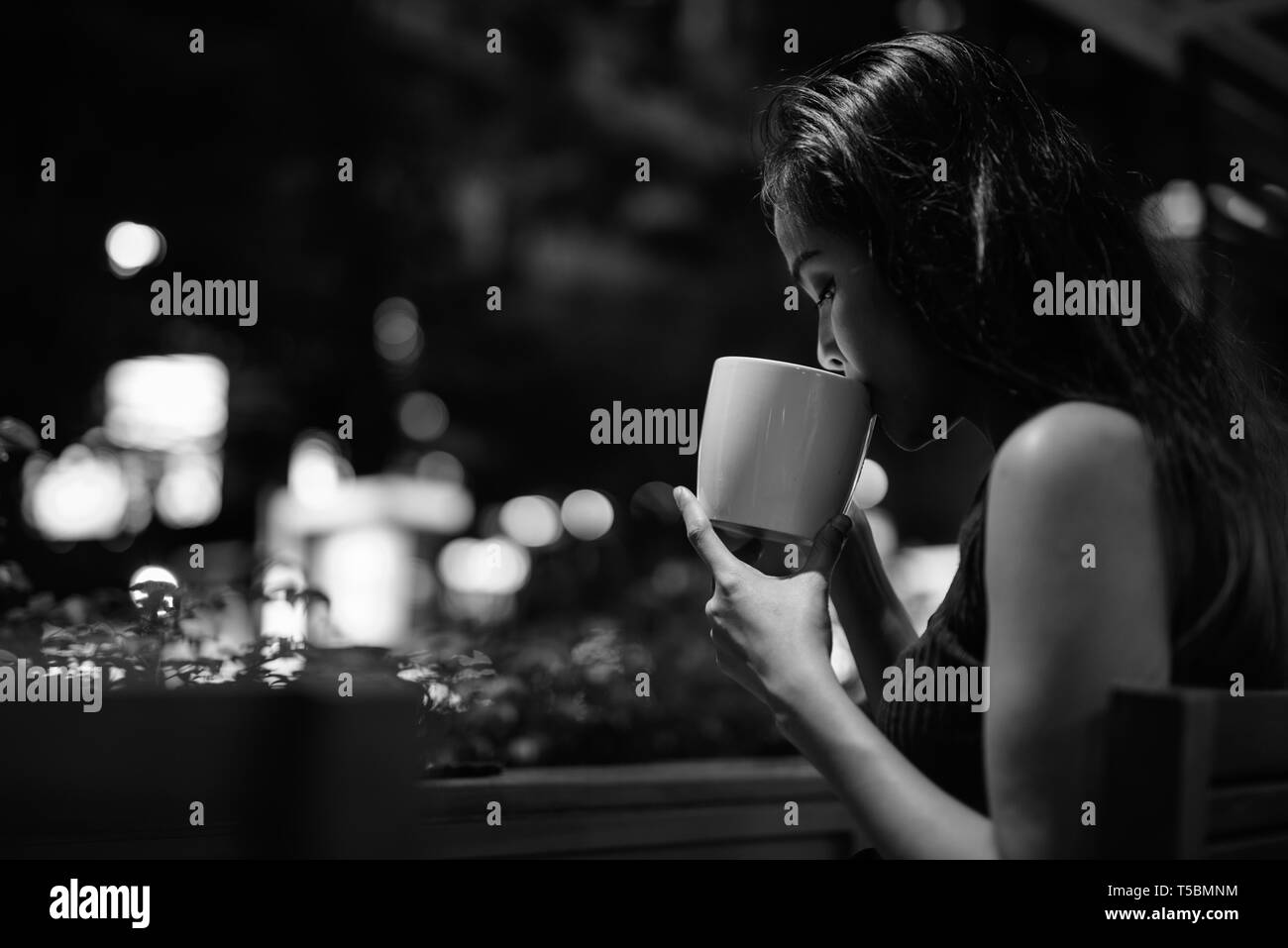 Junge schöne asiatische Frau entspannende im Coffee Shop in der Nacht Stockfoto
