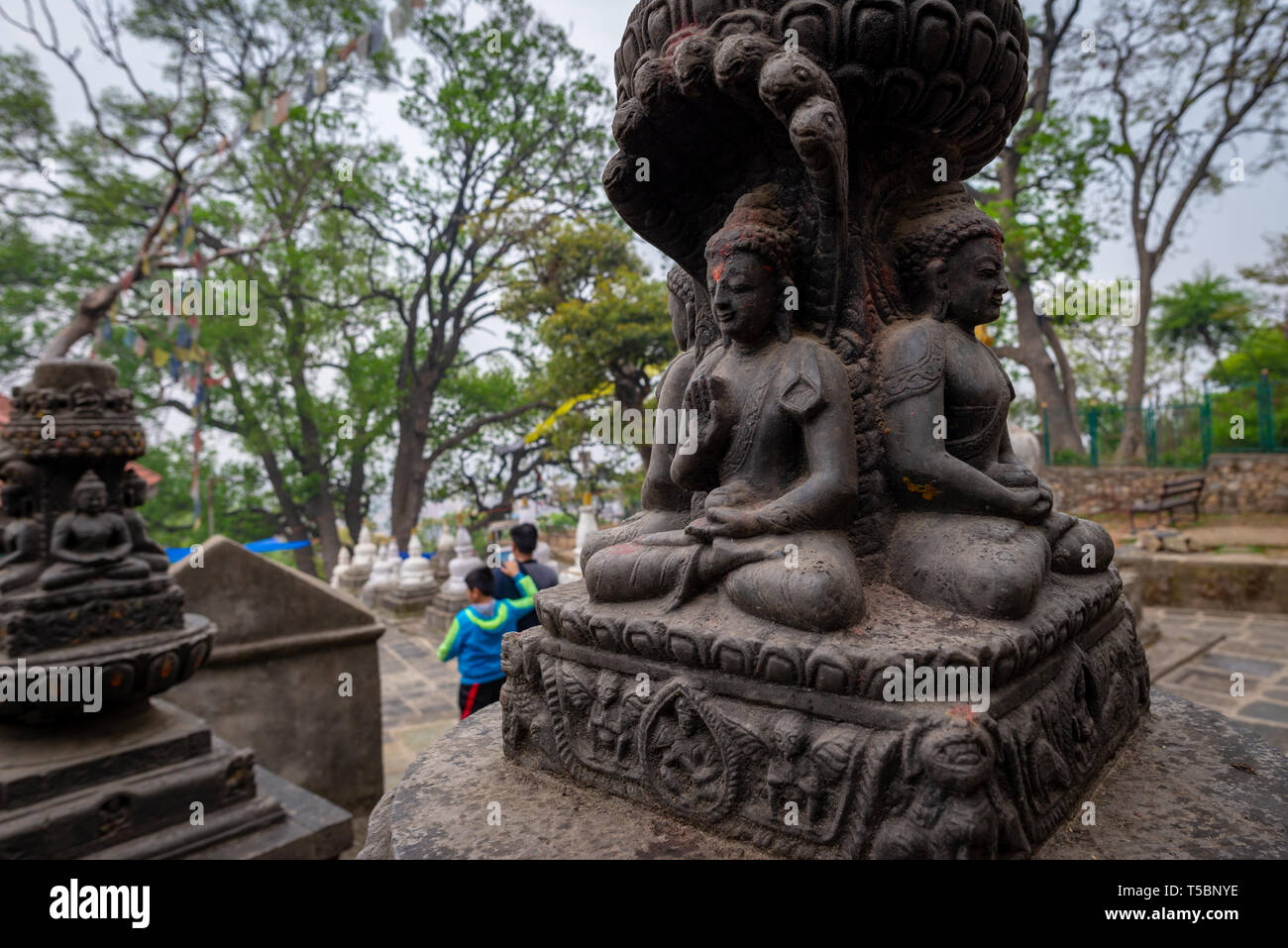 Vier Buddhas Skulptur und zwei Besucher an einem bewölkten Frühling Morgen am Monkey Tempel (Swayambhunath Tempel) in Kathmandu, Nepal Stockfoto