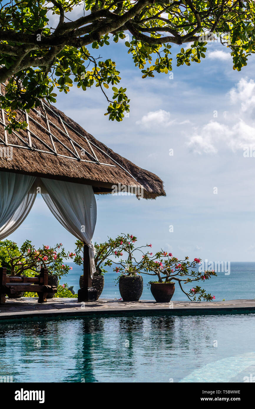 Indonesische Ballen mit Betten und Blumentöpfe mit Infinity Pool auf der Klippe mit Blick auf den Ozean. Lifestyle, Entspannung, tropische Ferien. Stockfoto