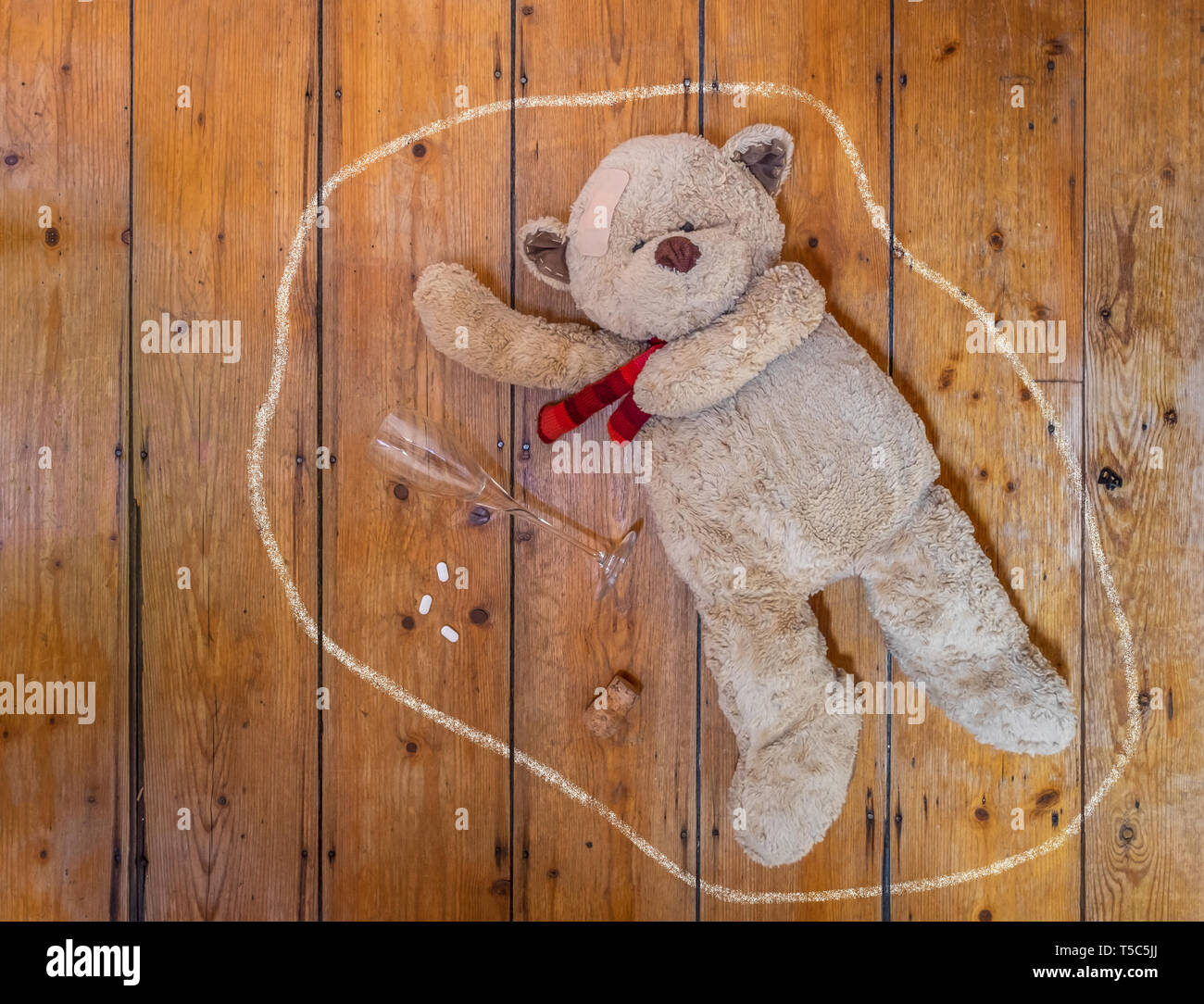 Teddybär liegend auf dem Boden mit einem leeren Glas, Pillen und Kreide. Konzept. Stockfoto