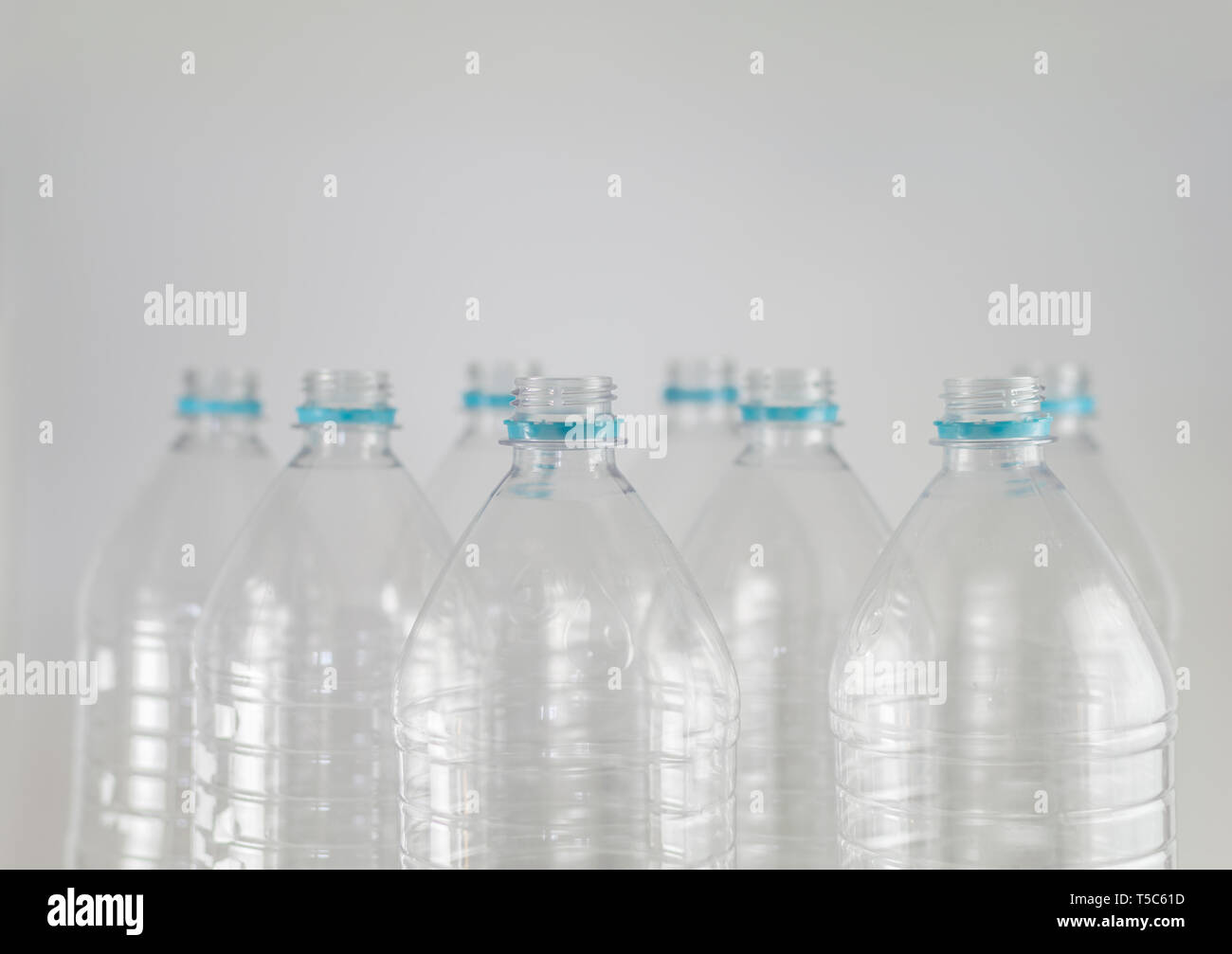 Engpässe einer Packung Liter und eine Hälfte der leeren Mineralwasser ohne Kappen nur mit dem Dichtring auf einem weißen Hintergrund. Wiederverwendung, Umweltfreundlich, E Stockfoto