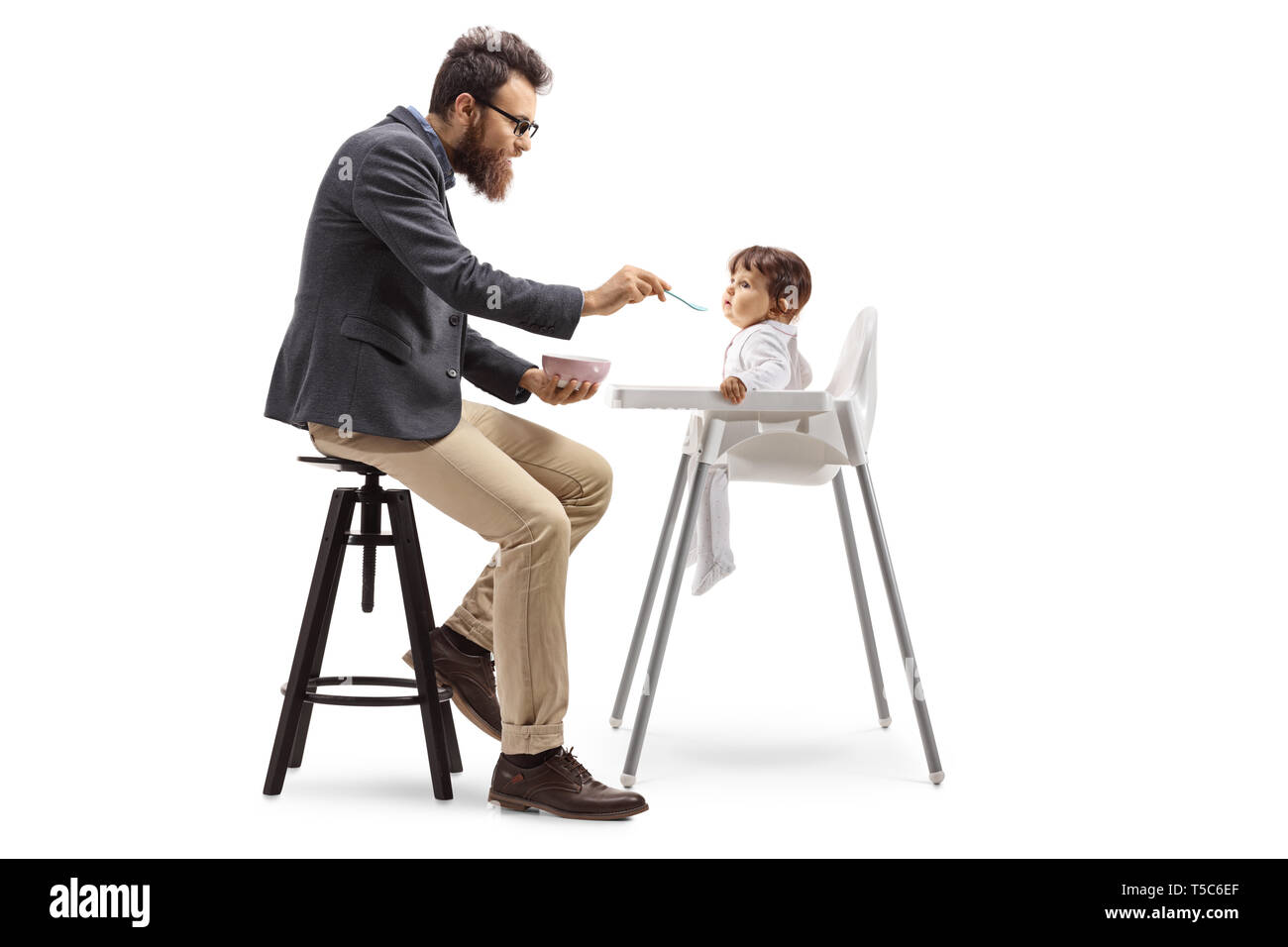 Volle Länge Profil Schuß eines Vaters sitzen und sein Baby füttern in einem stillen Stuhl auf weißem Hintergrund Stockfoto