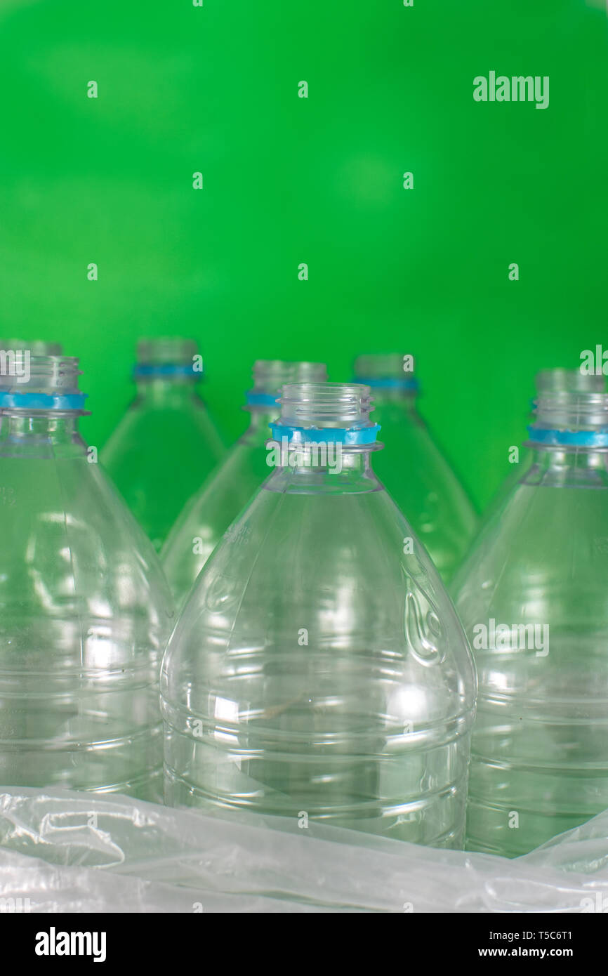 Verticam Bild einer Packung mit 8 leeren und recycelbaren Kunststoff Flaschen mit Wasser, ohne Deckel, blau Dichtung, in eine Plastiktüte, auf einem farbigen Hintergrund Stockfoto