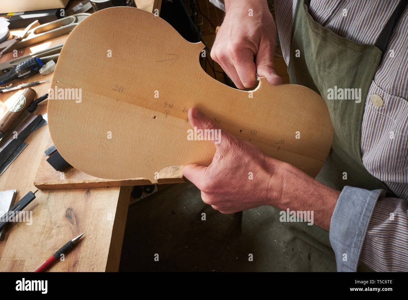 Geigenbauer bei der Arbeit in London, UK, schnitzen die Rückseite einer Violine Stockfoto