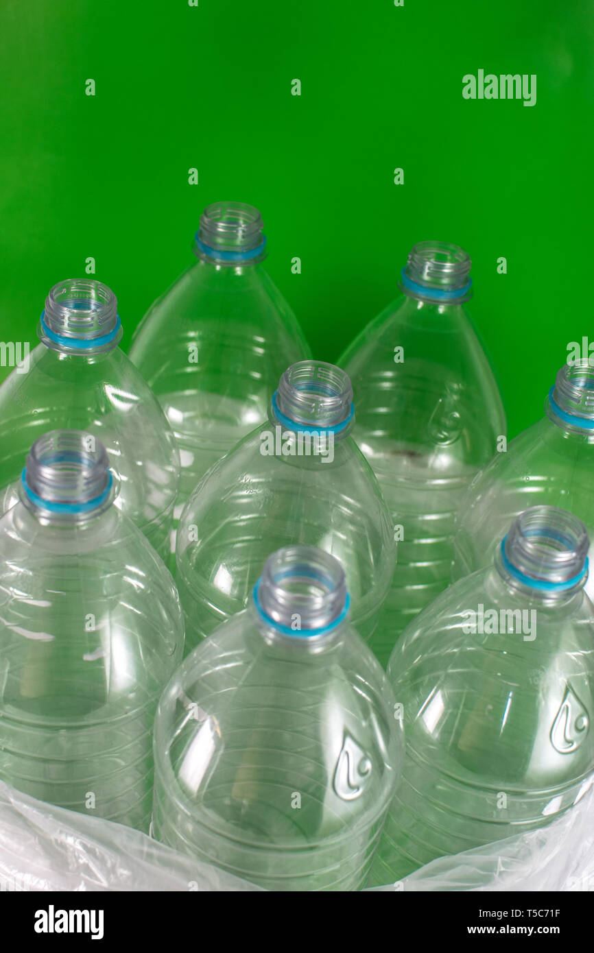 Verticam Bild einer Packung mit 8 leeren und recycelbaren Kunststoff Flaschen mit Wasser, ohne Deckel, blau Dichtung, in eine Plastiktüte, auf einem farbigen Hintergrund Stockfoto