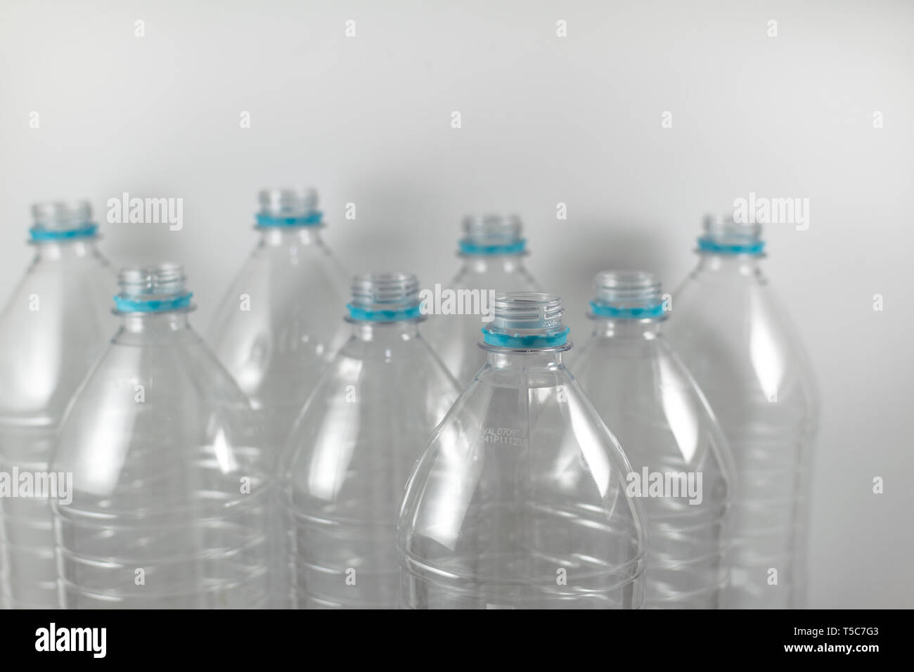 Packung mit ständigen Flaschen 0,1 Liter und eine Hälfte der leeren Mineralwasser ohne Kappen nur mit dem Dichtring auf einem weißen Hintergrund. Wiederverwendung, Eco Stockfoto