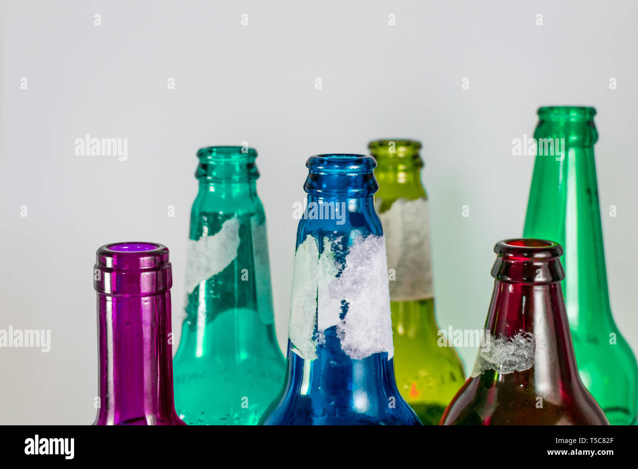 Bild der Engpass der leeren Bier und Wein Glasflaschen auf einem weißen Hintergrund. Grün, Gelb, Pink und Blau. Wiederverwendung, acoholism Stockfoto