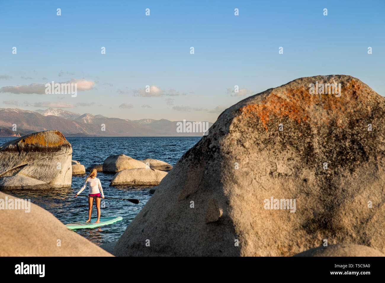 Aktive junge Frau paddleboarding über einen See. Stockfoto