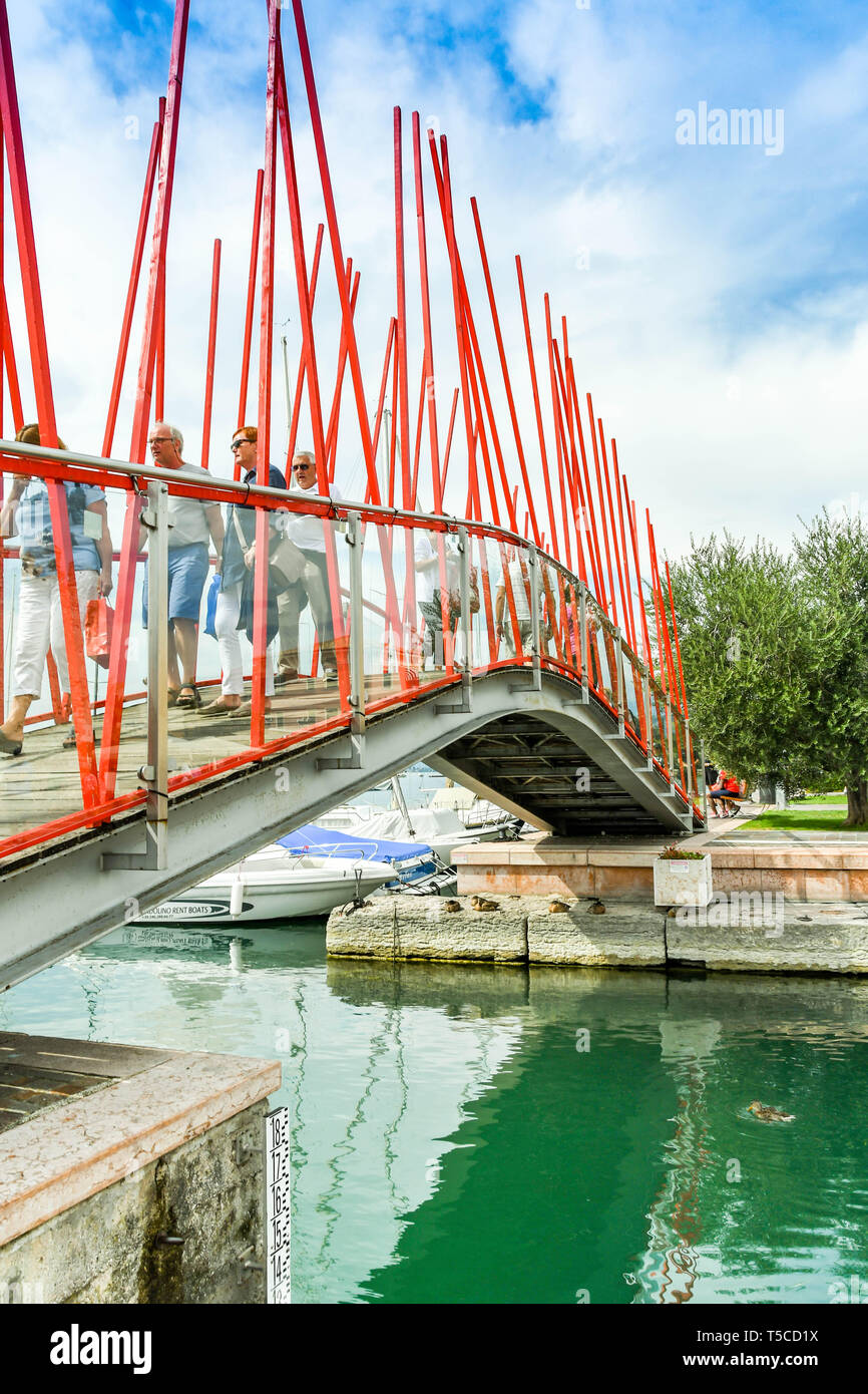 BARDOLINO, Gardasee, Italien - September 2018: Menschen zu Fuß über die Fußgängerbrücke über den Eingang zu dem kleinen Hafen in Bardolino am Gardasee. Stockfoto