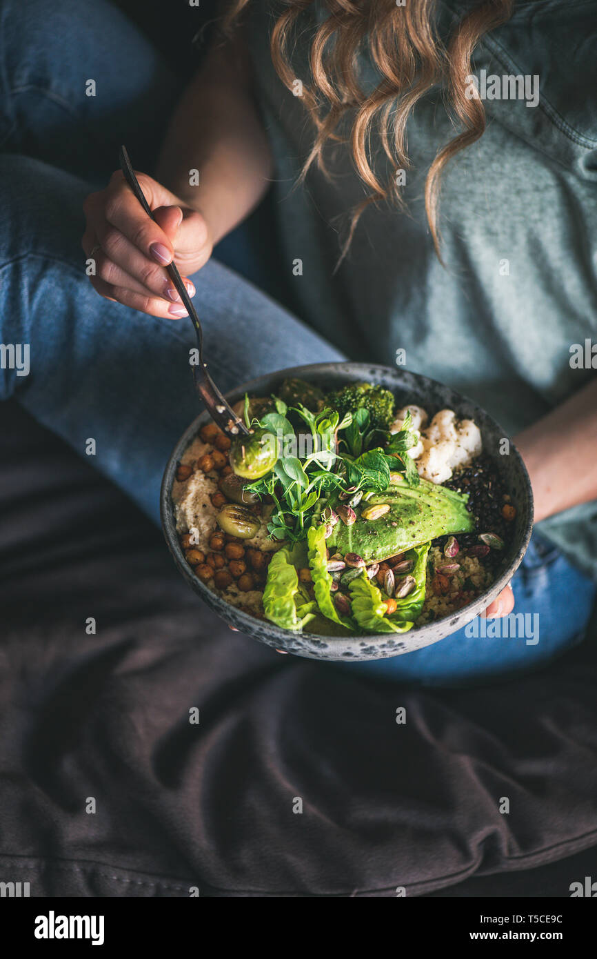 Frau sitzt und Essen vegan Gericht mit himmus und Avocado Stockfoto