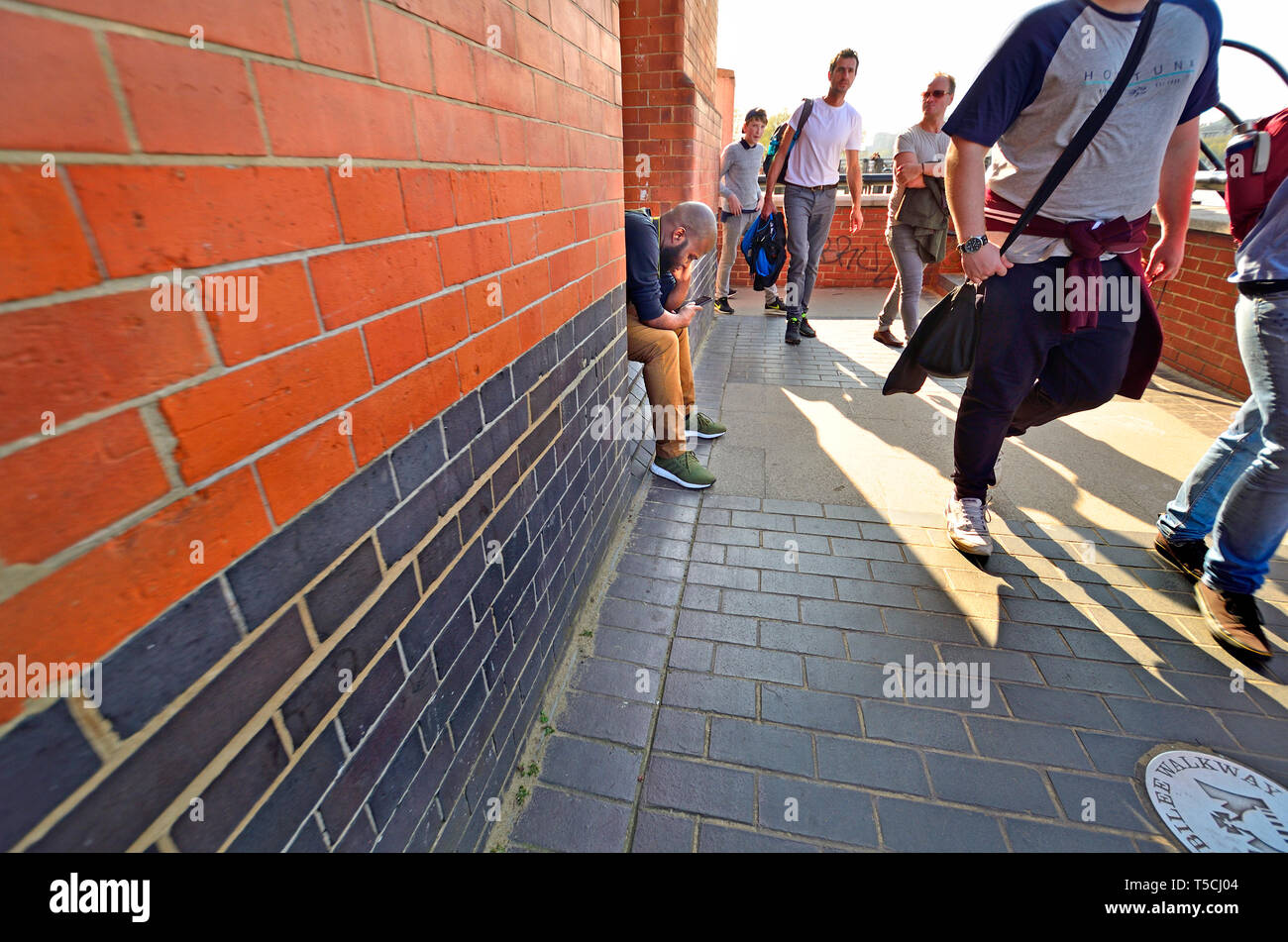 London, England, UK. Mann, auf sein Handy zu schauen, wie die Menschen früher gehen, South Bank Stockfoto