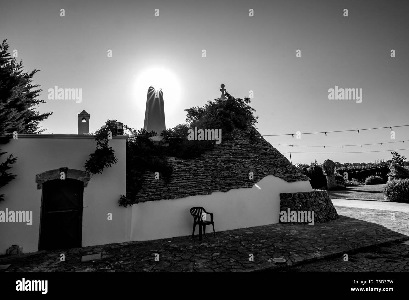 Stadtbild mit typischen herrliche Architektur der truli mit Kamin Lichtbeugung gegen die Sonne in der Region Apulien, in der Nähe von Alberobello, Süditalien. Warmen Sommermorgen, Schwarz und Weiß Stockfoto