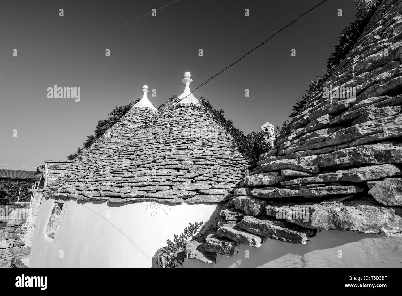 Stadtbild mit typischen herrliche Architektur der truli mit schöne Dächer beleuchtet von der Sonne in Apulien, in der Nähe von Alberobello, Süditalien. Warmen Sommermorgen, Schwarz und Weiß Stockfoto