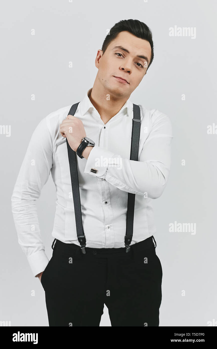 Stilvolle moderne, junge brunette Mann im weißen Hemd, schwarze Hosen und  Hosenträger auf weißem Hintergrund Stockfotografie - Alamy