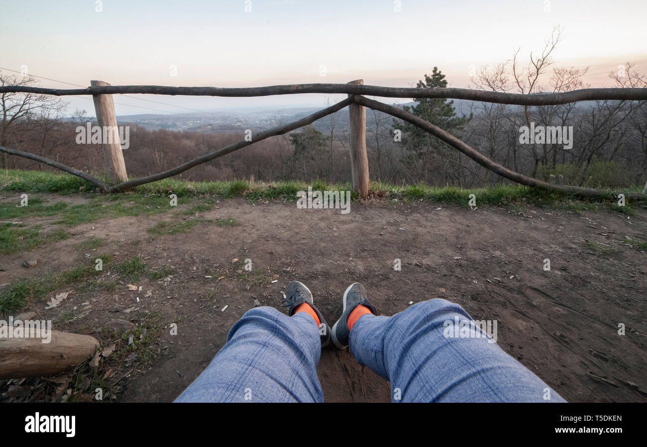 In der Nähe der Schuß von gespreizten Beine (Jeans), sitzen. Im Vordergrund ist. Person nicht sichtbar, erste Person anzeigen. Stockfoto