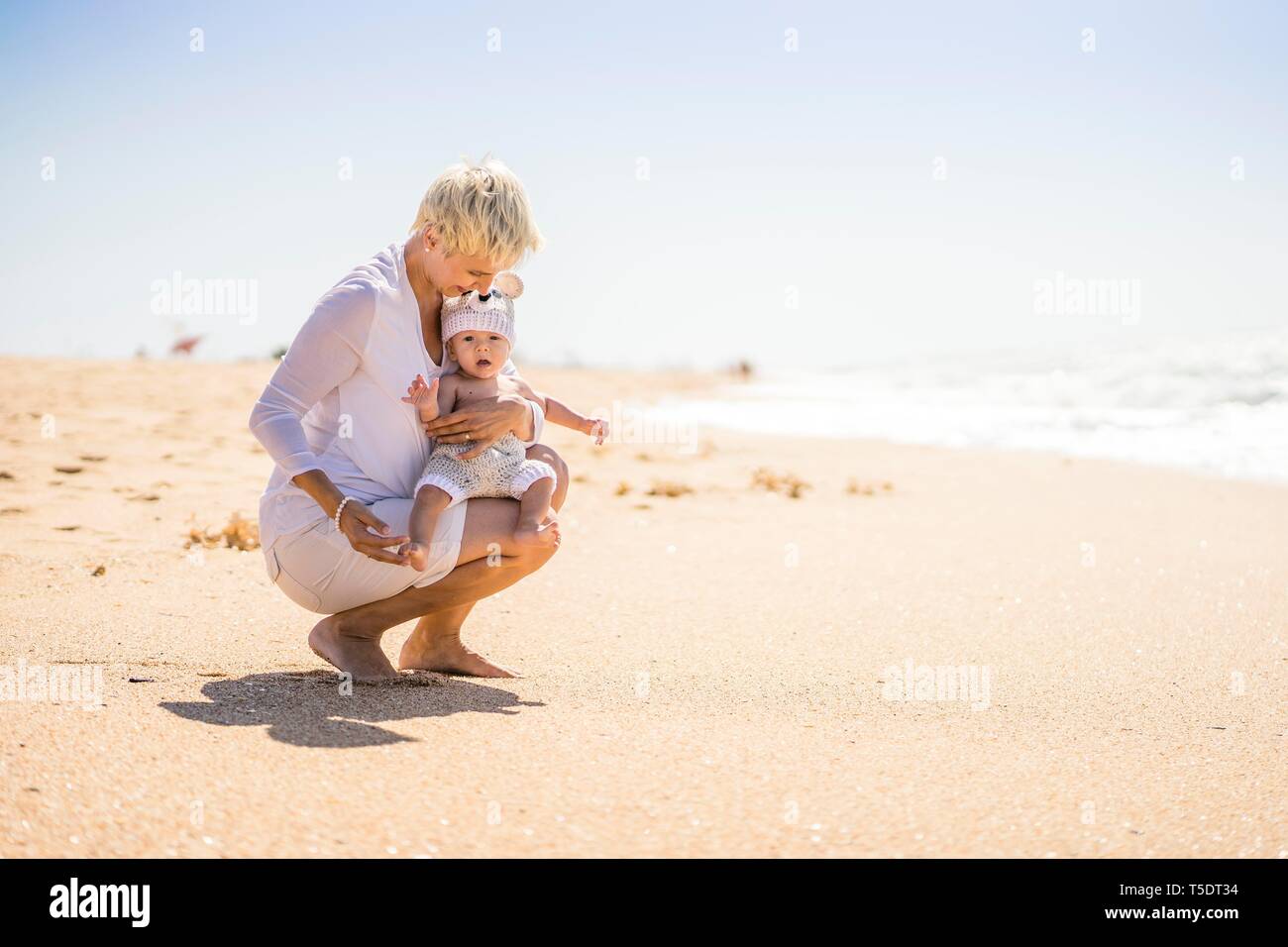Attraktive Blondine Mutter mit 4 Monate alten Baby auf den Strand, Portugal Stockfoto