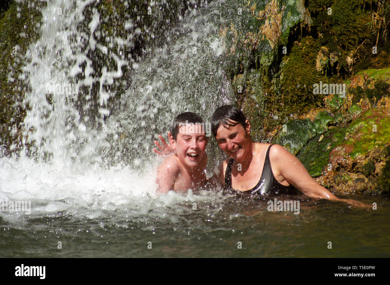Mutter und Sohn mit einem kalten unter einem Wasserfall in den Gorges du Terminet, Corbieres, Aude, Royal, Frankreich. MODEL RELEASED Stockfoto