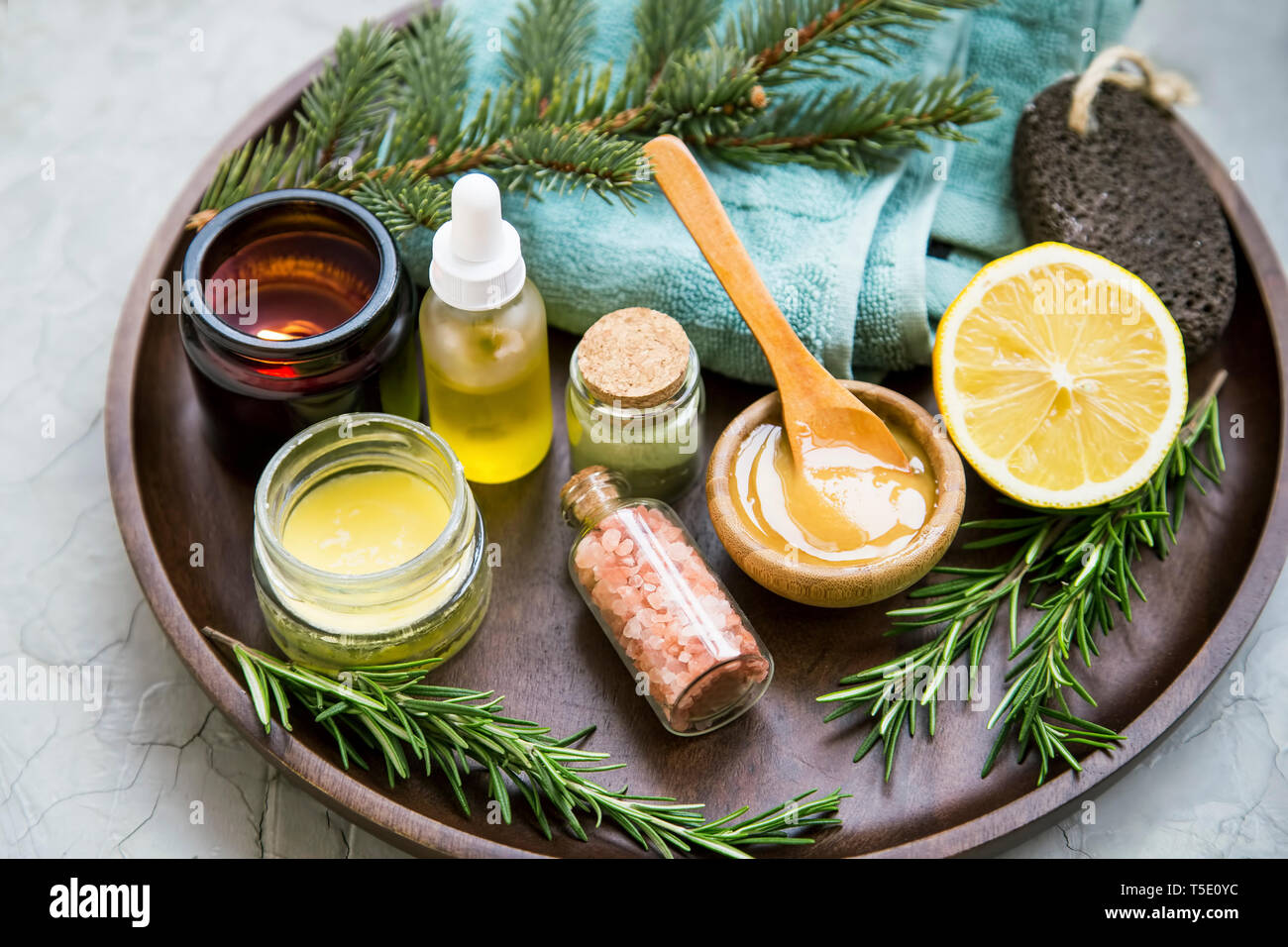 Natürliche organische spa Zutaten mit Manuka Honig, ätherisches Öl Flasche, Lehmpulver, Badesalz, Baumwolle Handtuch, Zitrone, Rosmarin und Pinie Niederlassungen Stockfoto