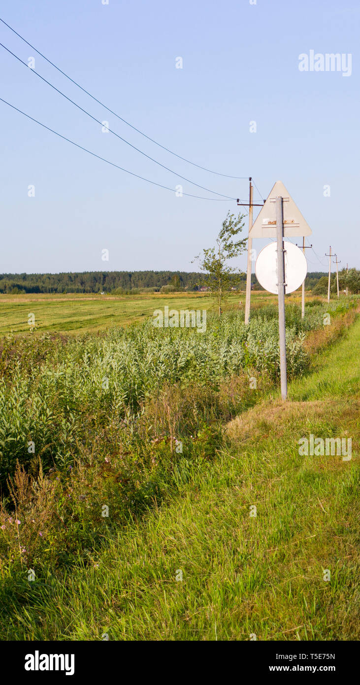 Normalpapier mit grünem Gras elektrischen Polen und Schild im Sommer. Hintergrund. Natur. Stockfoto