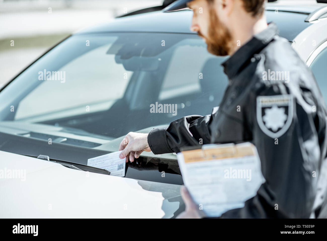 Polizist, fein für falsches Parken auf der Windschutzscheibe des Autos am Straßenrand Stockfoto