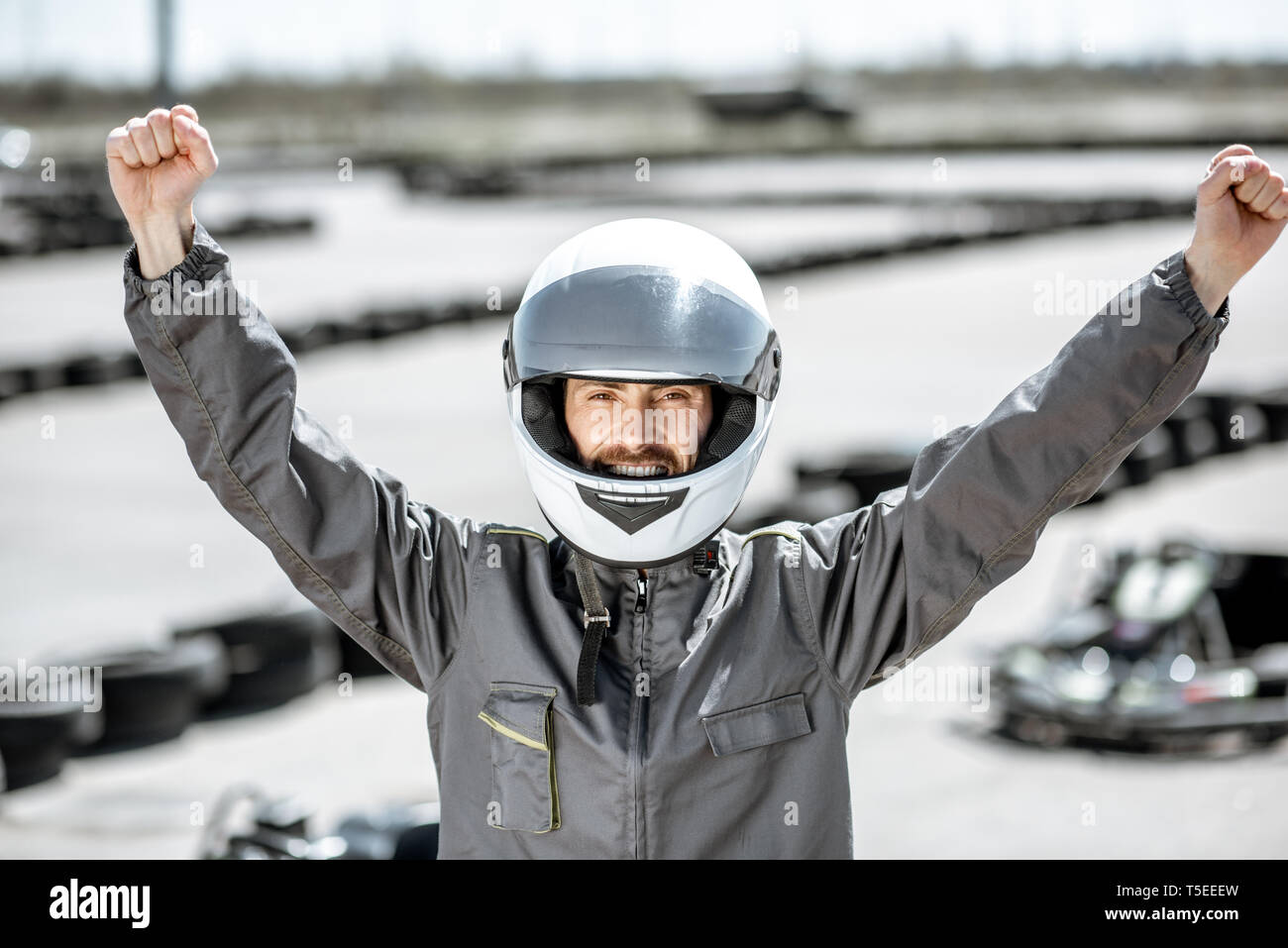 Portrait Of Happy Racer in sportschutzausrüstungen als Sieger eines Go-Kart-Rennen im Freien Stockfoto