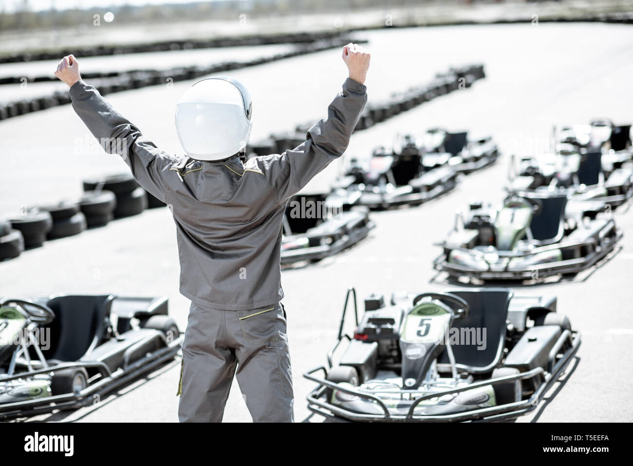 Portrait Of Happy Racer in sportschutzausrüstungen als Sieger eines Go-Kart-Rennen im Freien Stockfoto