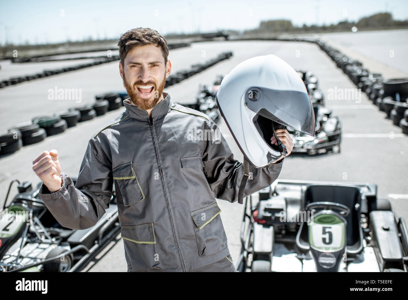 Portrait Of Happy Racer in sportschutzausrüstungen als Sieger eines Go-Kart-Rennen im Freien Stockfoto