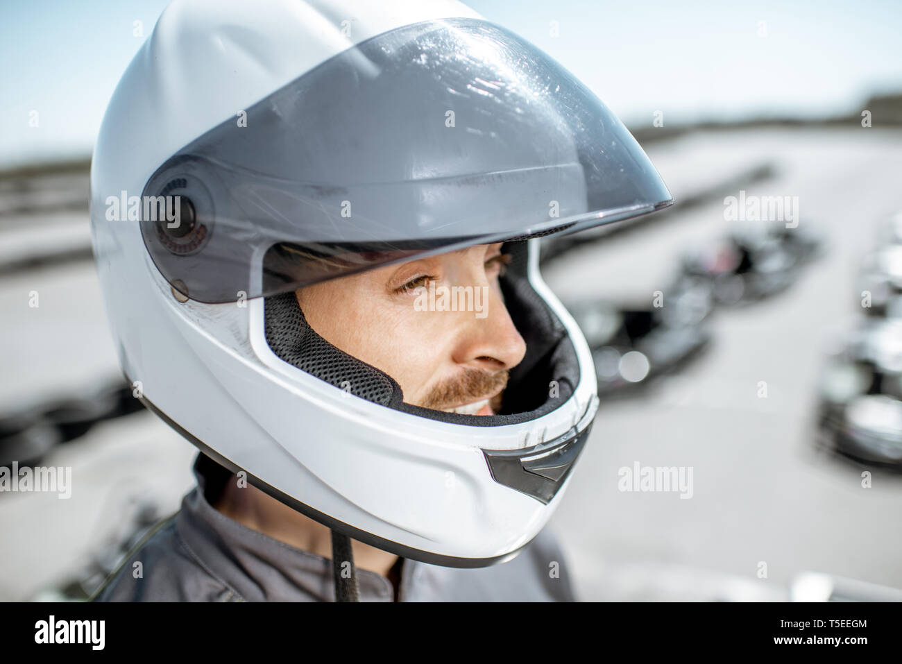 - Nahaufnahme Porträt einer männlichen Racer in Schutzhelm stehen auf der Kartbahn im Freien Stockfoto