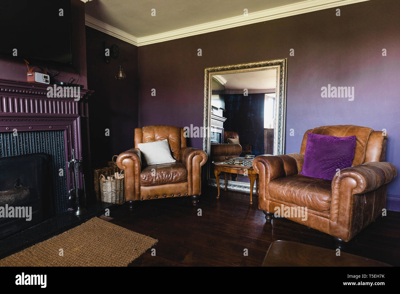 Weitwinkel Blick in das Innere von einem Wohnzimmer. Die Wände sind Lila und es gibt zwei braunen Leder arm seitliche Stühle nebeneinander. Stockfoto